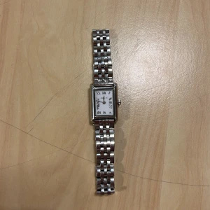 Silverfärgad klocka med länkarmband - Stilren klocka från Mockberg med rektangulärt vitt ur och romerska siffror. Klockan har ett klassiskt silverfärgat länkarmband i metall och en elegant, tidlös design som passar till många olika stilar.☺️ Man får med så man kan ställa in den efter sin egen storlek! Äkta silver! ☺️Nypris var 2000kr och har lagt till 180 för att ställa in.