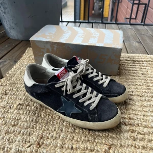 Golden Goose Sneakers - Golden Goose Superstar sneakers i mörkblå mocka. Klassisk stjärndetalj på sidan och GGDB made in Italy logga på plösen. Skorna är i väldigt fint skick trots en del användning. Storlek 43EU. OG medföljer.