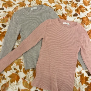Ribbad långärmad tröja Primark - Två ribbade långärmade tröjor från Primark i storlek S. En är ljusgrå och den andra är ljusrosa. Båda har rund hals och är gjorda i mjuk bomullsmix, perfekta för lager-på-lager och chill dagar. Snyggt slim fit och sköna att bära.