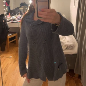 Blå stickad kofta från Rabalder - Säljer en chill blå stickad kofta från Rabalder i storlek S. Koftan har snygg asymmetrisk knäppning med fyra stora knappar och en bred krage. Materialet är grovstickad bomull och modellen är loose fit med långa ärmar. Perfekt för lager-på-lager under hösten och vintern.