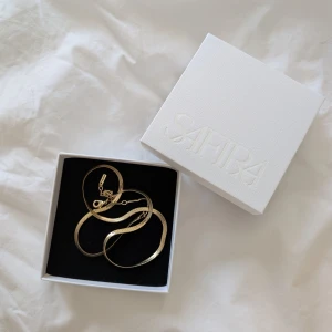 Guldigt platt halsband från Safira - Säljer ett stilrent och platt guldigt halsband från Safira. Oanvänt!