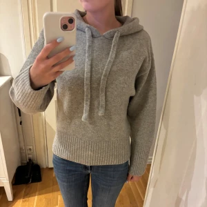 Stickad hoodie  - Mysig grå hoodie från Zara i stickat material med huva och snörning. Perfekt inför vintern. Bara använd en gång