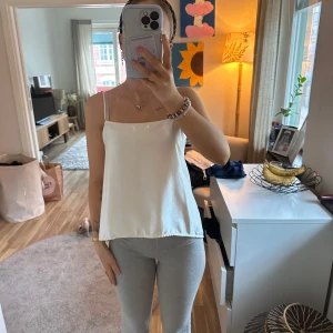 Vit siden-linnetopp med öppen rygg - Supersöt vit linnetopp i siden med tunna axelband och öppen rygg som knyts baktill. Du kan alltså välja hur mycket ”öppen” rygg du vill ha asså den är så sexig!! Finns några små fläckar och någon tråd så den är använd absolut!😆- syns lite på bild 4❤️