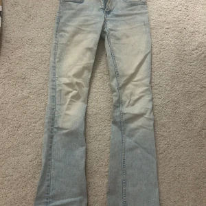 Ljusblå bootcut jeans - Säljer ett par ljusblå jeans med bootcut passform. Jeansen har klassiska fem fickor och är tillverkade i jeansmaterial. De har en lätt tvättad look och vida ben nertill för en retro vibe.