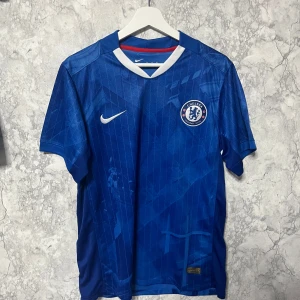 Chelsea Palmer 10 Nike fotbollströja M - Chelsea FC matchtröja med Palmer och nummer 10 på ryggen. Blå med vita och röda detaljer, tillverkad i lätt Dri-FIT material som andas. Snyggt geometriskt mönster och klubbmärke på bröstet. Perfekt för dig som vill representera laget på läktaren eller planen.