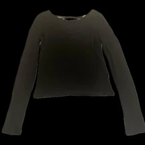 Svart långärmad topp med snörning på ryggen  - Säljer en svart långärmad topp med snygg snörning på ryggen. Materialet är lite genomskinligt.