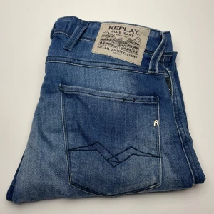 Replay Anbass jeans  - Snygga blå Replay Anbass jeans i slim fit med klassisk femficksdesign och coola detaljer på bakfickan. Jeansen har en mellanblå tvätt och är tillverkade i mjukt bomullsmaterial. Perfekta för dig som gillar en smalare passform och stilren look.