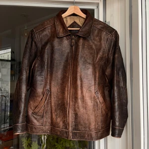 Brun skinnjacka strl S-M - Säljer denna fina läderjacka då den tyvärr är för liten för mig. Väldigt fin jacka och väldigt snygg fade på lädret. Tyvärr har fodret i ena fickan och ärm gått sönder, men går att sy om man är engagerad att göra det. Utöver det är resten av jackan i superbra skick. Sitter lite för litet på mig och jag brukar ha strl L-XL i kläder, så detta är en S-M jacka. 