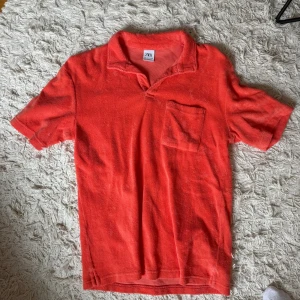 Orange/Korall frotté piké från Zara - Säljer en orange t-shirt från Zara i mjuk frotté. Pikén har korta ärmar, klassisk krage och en bröstficka. 