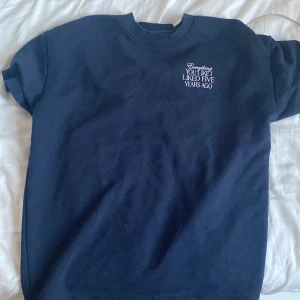 Mörkblå t-shirt med tryck New Garments - Mörkblå t-shirt från New Garments i storlek XS. Framsidan har ett stort vitt tryck med texten 'Everything you like I liked five years ago'. T-shirten har rund hals och korta ärmar, tillverkad i mjuk bomull. Perfekt för dig som gillar statement-plagg.