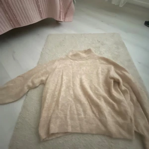 Beige glittrig polotröja från H&M - Säljer en beige polotröja från H&M i storlek S. Tröjan är stickad med glittriga inslag och har en hög krage. Den är långärmad och har en loose passform