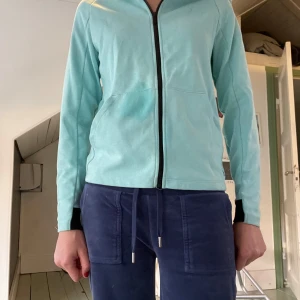 Ljusblå zip-hoodie från SOC - Säljer en ljusblå/turkos hoodie  från SOC med hel dragkedja och huva. Tröjan har svarta muddar vid ärmsluten och praktiska fickor framtill. Perfekt för chill dagar eller när du vill ha något bekvämt och snyggt på dig. Den funkar bra att sporta i eller ha vardagligt. Storlek 152.
