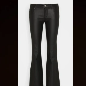 Svarta lågmidjade bootcut byxor i skinnlook - Snygga svarta lågmidjade byxor med bootcut passform och hög midja. Byxorna har en cool skinnlook och klassiska fickor både fram och bak. Perfekta för dig som vill ha en trendig siluett med lite extra edge. Passar till både sneakers och boots. 