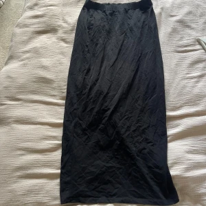 Svart långkjol från NLY Trend - En stilren svart långkjol från NLY Trend i storlek S. Kjolen har en rak och enkel design med elastisk midja med slits bak! 
