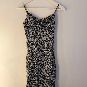 Bershka klänning  - Söt, svart och vit blommig klänning med smala axelband och en liten slits nedtill. Klänningen har en smickrande passform. Storlek M men skulle säga något liten i storlek, mer en S. Fint skick