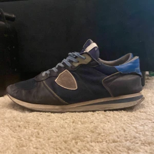 Blå Philippe Model sneakers - Säljer ett par snygga Philippe Model sneakers i mörkblått med ljusblå detaljer och grå inslag. Skorna har snörning, rund tå och platt sula. Materialmix av skinn och syntet med mesh på ovansidan. Märkeslogga på hälen och sidan. Tveka inte med att höra av dig/ Alex🔥box ingår!