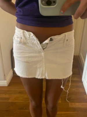 Vit jeanskjol  - Säljer en vit kort jeanskjol med rå, fransig kant och slitna detaljer. Perfekt för dig som gillar en avslappnad och trendig stil. Säljer då den är för liten
