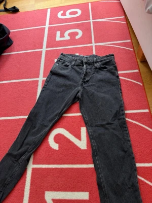 Svarta relaxed jeans från Jack & Jones - Säljer ett par svarta relaxed fit jeans från Jack & Jones, modell Chris. Jeansen har klassisk femficksdesign, bälteshällor och knappgylf. 