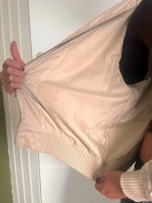 Beige bomberjacka med dragkedja - Jag svär den är finare strykt!⭐️ Beige bomberjacka med dragkedja framtill och ribbade muddar vid ärmslut och midja. Jackan har en klassisk bomberpassform.