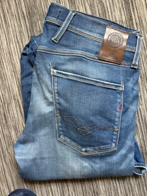 Replay anbass - Snygga blå slim fit jeans med ljusa slitningar och klassisk femficksdesign. Jeansen har en läderpatch bak i midjan och kontrastsömmar på bakfickan. Tillverkade i denim med en modern tvättad look som ger en avslappnad stil. Se skador på bilderna, därav priset. Storlek 31 34. Hör av dig vid frågor// kan gå ner i pris vid snabb affär!😃/ Milton