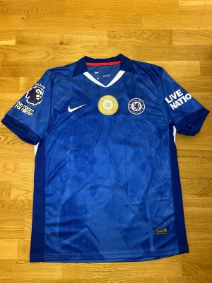 Chelsea matchtröja João Pedro #20 - Snygg blå Chelsea matchtröja från Nike med João Pedro och nummer 20 på ryggen. Tröjan har Premier League-märke på ärmen, FIFA-märke på bröstet och klubbmärke fram. Tillverkad i lätt och ventilerande material, perfekt för fotboll eller träning.
