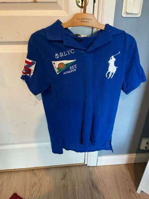 Ralph Lauren piké - Säljer en blå RL piké som passar perfekt nu till sommaren. Den är enligt mig mycket snygg men också unik och passar bra om man vill sticka ut lite extra! Säljer den till ett väldigt bra pris då skicket är bra och motsvarande nypris är ganska dyrt!