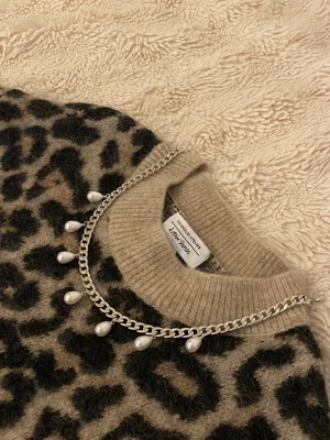 Silverfärgat halsband med pärlor - Snyggt halsband i silverfärgad rostfritt med droppformade pärlor som hänger längs kedjan. Perfekt för att ge en trendig touch till din outfit. Kedjan har en chunky känsla och pärlorna ger en elegant kontrast.