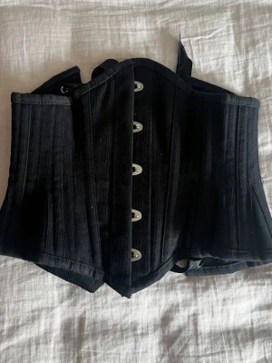 Stålbenad korsett  - Otroligt vacker och välgjord korsett med stålben i. En kortare modell och sitter som en waist cincher. 20 tum vilket passar en xs. Använt sparsamt men banden är klippta något pga att de var väldigt långa, men inget som påverkar den. 