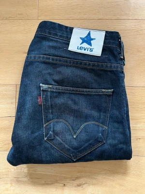 Rare Levi’s Blue Star 500 Jeans – W34 L36 – Made in Croatia – Europe Collection - Ovanlig Levi’s Blue Star-kollektion från mitten av 2000-talet. Modell 05000-4006. Originalpatch med blå stjärna och Blue Star-tryck i fickpåsen. Tillverkade i Kroatien. Fint skick
