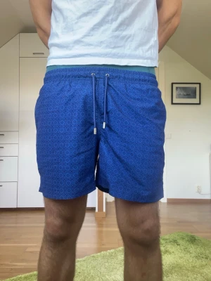 Blå mönstrade badbyxor  - Mörkblå badbyxor från märket Decisive. Strl S. Inga defekter. Modellen är 178 cm och väger 77 kg. Hör gärna av dig vid frågor!