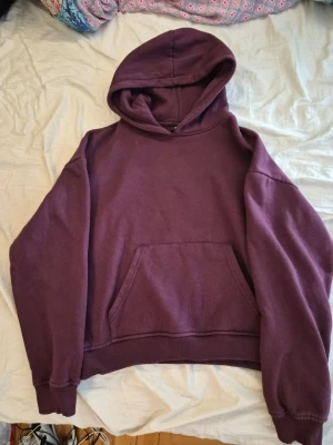 Lila hoodie från 157 med huva - Mysig lila hoodie från 157 med stor känguruficka framtill och klassisk huva. Tröjan har ribbade muddar vid ärmslut och nederkant. Perfekt för chill dagar eller när du vill ha en enkel och snygg look.