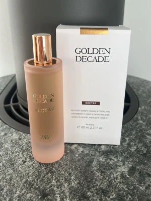 Golden Decade Nectar parfym 80 ml - Golden Decade Nectar från Zara är en parfym i en matt, ljusrosa glasflaska med gulddetaljer och matchande vit kartong. Doften har inslag av röda frukter, apelsinblomma och jordgubbsblomma, vilket ger en fräsch och söt känsla. Flaskan rymmer 80 ml.