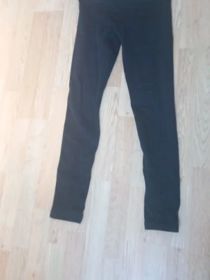 Svarta basic leggings - Ett par svarta leggings med hög midja och smal passform. Tillverkade i ett stretchigt material som sitter skönt mot kroppen. Perfekta att matcha med oversized tröjor eller hoodies.