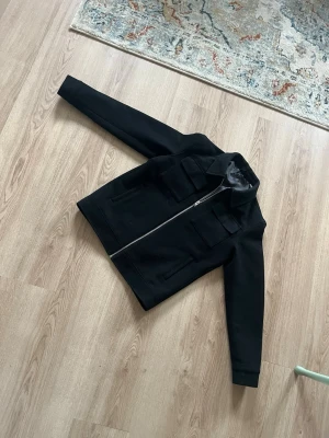 Svart overshirt med fickor och dragkedja - Svart jacka från Jack and Jones. Rak och någorlunda liten i passformen. 