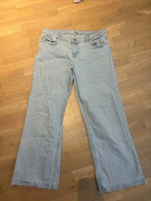 Ljusblåa vida jeans från NA-KD - Säljer ett par ljusblåa lågmidjade jeans från NA-KD med vida. Perfekta för en avslappnad och trendig look. Är i storlek 40 men skulle säga att de också skulle passa en 38