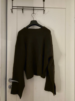 Mörkbrun oversized stickad tröja - En oversized stickad tröja i mörkbrunt med breda, långa ärmar och ribbstickade muddar vid ärmslut och nederkant. Tröjan har en avslappnad passform och rund halsringning. Perfekt för lager-på-lager och chill höststil.