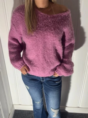 Ljusrosa fluffig stickad tröja - Mysig stickad tröja i ljusrosa med lös passform och bred v-ringning💗. Tröjan har långa ärmar och ribbade muddar vid ärmslut och nederkant. Materialet är fluffigt och ger en soft känsla, perfekt för kyliga dagar eller sena sommarkvällar☀️
