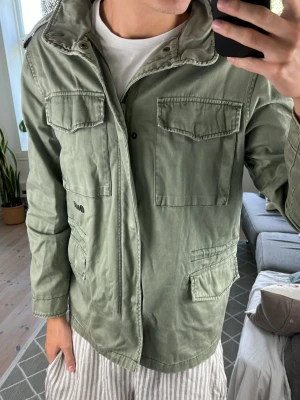 Fieldjacket olivgrön  - Super snygg och trendig! Perfekt under sommarkvällarna. Storlek XL men den sitter mer som L. Mått: A:50 B:52 C:54 D:68 (cm) Skriv vid fundering 😇🙌