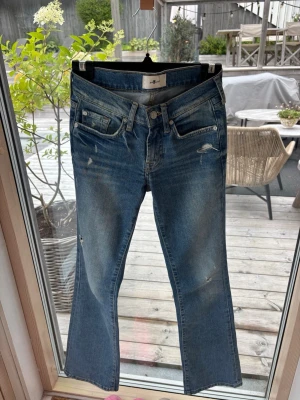 Blå bootcut jeans med slitningar - Säljer ett par blå bootcut jeans med lätt slitna detaljer och klassisk femficksdesign. Jeansen har en något utsvängd passform nedtill och snygg tvättad look. Jeansen är köpta i Lasvegas. Nypris 800kr 