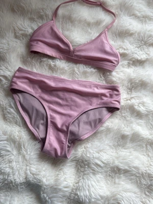 Ljusrosa V-ringad bikini - Snygg bikini med lite glitteraktikt material. Köpte i slutet av förra sommaren men denna sommar blev den för liten. 🥰 man knäpper ihop där bak. 