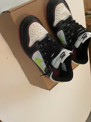 Nike sneakers svart/vit med limegrönt - Snygga Nike sneakers med svart och vitt läder, detaljer i vinrött och limegrönt på sidan. Bra skick men ingående orginallåda, priset går att diskuteras vid snabb affär