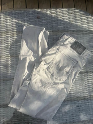 Ljusgrå raka jeans - Säljer ett par ljusgrå jeans med rak passform och klassiska fem fickor. Jeansen har en enkel design utan slitningar och är tillverkade i ett mjukt denimtyg. Perfekta för en clean och stilren look.