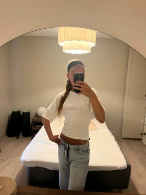 Vit croppad topp med knyt - Säljer en vit croppad topp med knyt i midjan. Toppen har rund halsringning och halvlånga ärmar. Perfekt till jeans eller kjol för en clean och enkel look.