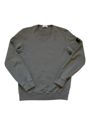 Stone island tröja  - Stone Island Junior Sweatshirt  Snygg Stone Island Junior sweatshirt i khaki, i nytt skick. Stilren och lättmatchad modell med den ikoniska Stone Island-detaljen. Storlek 170, passar ungefär S/M.  • Khaki • Storlek 170 – passar S/M • Nytt skick • Nypris ca 3 000 kr