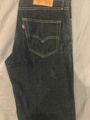 Mörkblå raka jeans från Levi's - Snygga mörkblå jeans från Levi's med klassisk femficksdesign och kontrastsömmar. Jeansen har rak passform och är tillverkade i slitstark denim. Perfekta för dig som gillar tidlös stil och vill ha ett par jeans som funkar till det mesta.