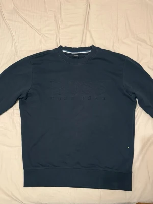 Mörkblå sweatshirt från Hugo Boss - Mörkblå Hugo Boss sweatshirt i storlek L med broderad BOSS-logga framtill. Bra begagnat skick.