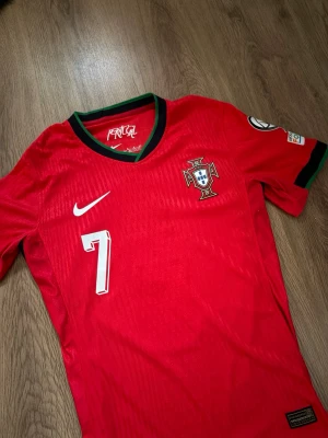 Ronaldo Fotbollströja Portugal - Snygg röd Porugal fotbollströja med Ronaldo #7 på ryggen. Tröjan är från EM2024 och är playerversion (mycket bättre kvalitet). Skick som nytt. Storlek S! Skriv om ni har några funderingar!😃