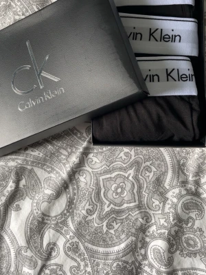 Svarta kalsonger från Calvin Klein - Trepack svarta kalsonger från Calvin Klein med vit resår och svart logga. Klassisk boxermodell med bekväm passform och stilren design. Perfekta för dig som gillar enkel och snygg stil. Kommer i originalförpackning.