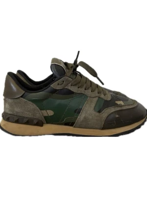 Valentino Rockrunners  - Snygga Rockrunners från Valentino med camomönster i grönt, svart och beige. Skorna har detaljer i mocka och läder, samt en beige sula med nitar på hälen. Perfekta för dig som vill sticka ut med exklusiv streetstyle.( skon har en skavank på tån(se bild) men går att åtgärda)