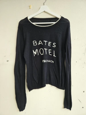 Stickad tröja i 100% silke - Superfin tunn stickad tröja i 100% silke. Svart med vit text 'Bates Motel Vacancy'. Fint skick. Litet ihopsytt hål på baksidan som knappt syns. Storlek L skulle jag säga. Från Zadig & Voltaire men har inga lappar kvar tyvärr.